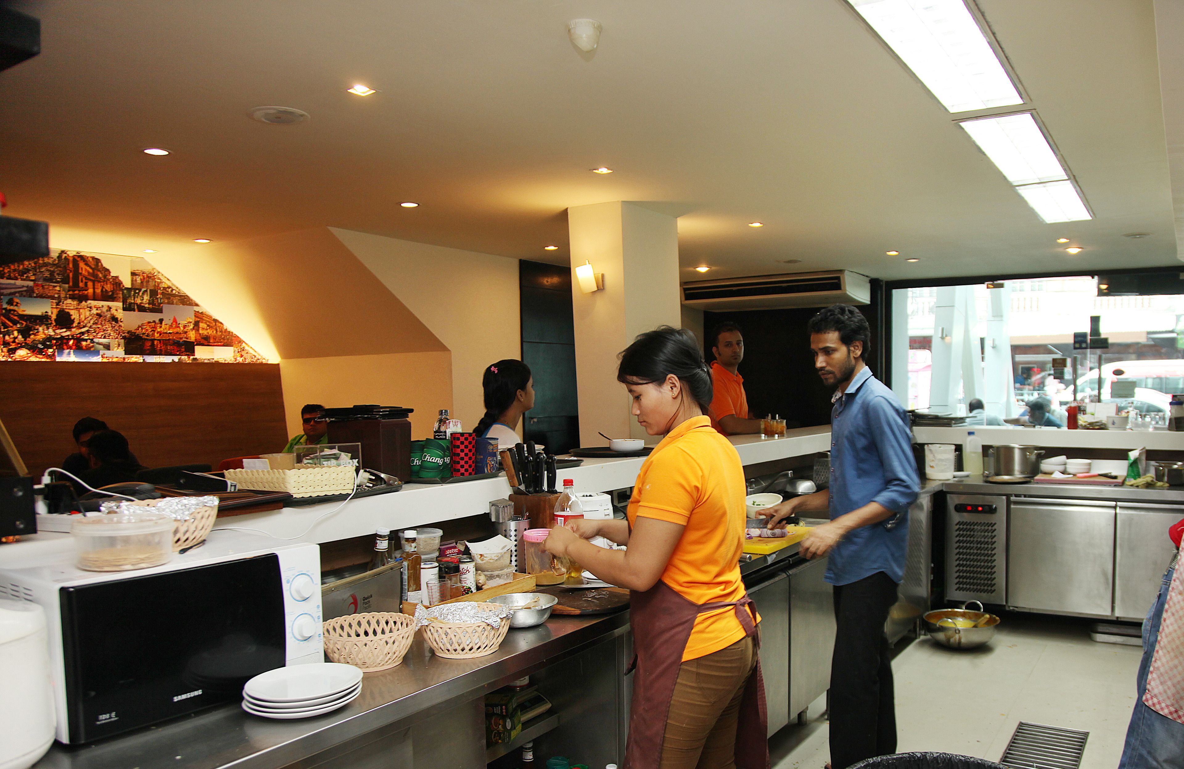 A modern kitchen with stainless steel appliances, a variety of cooking utensils, and a display of food items on the counter.
