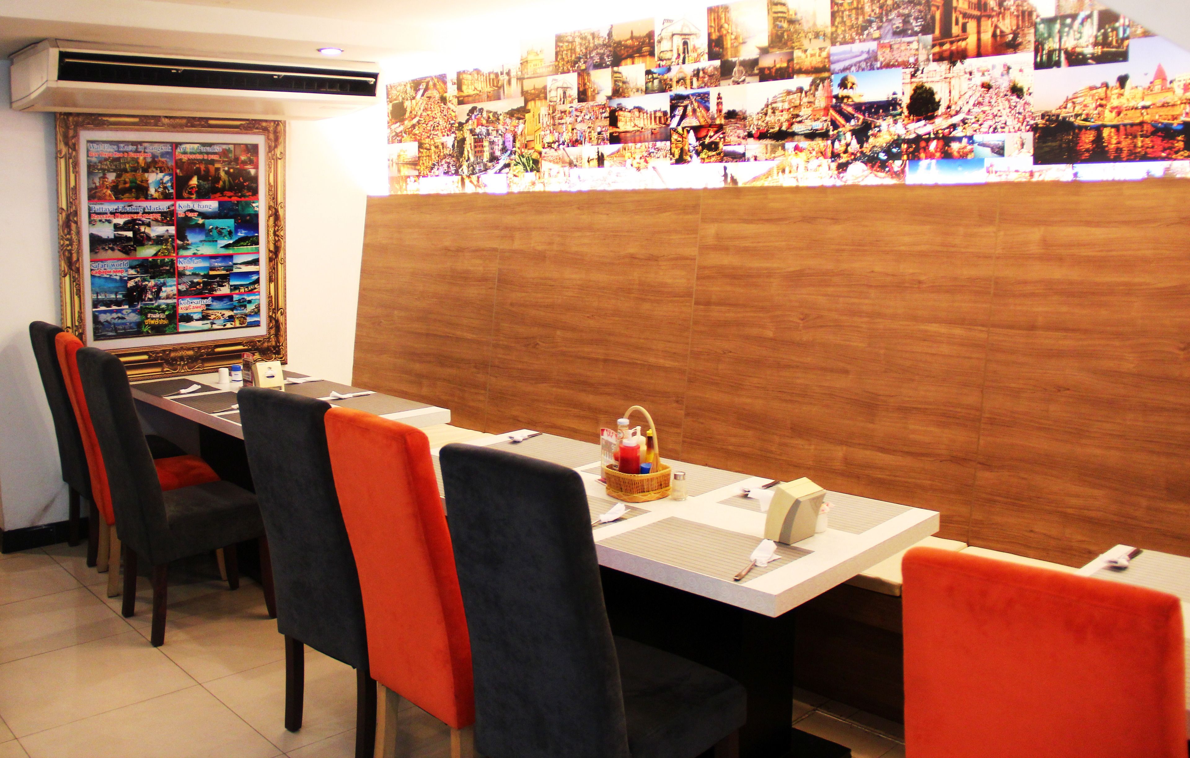 Un restaurant avec une longue table, de nombreuses chaises et un mur décoré d’un collage de photos.