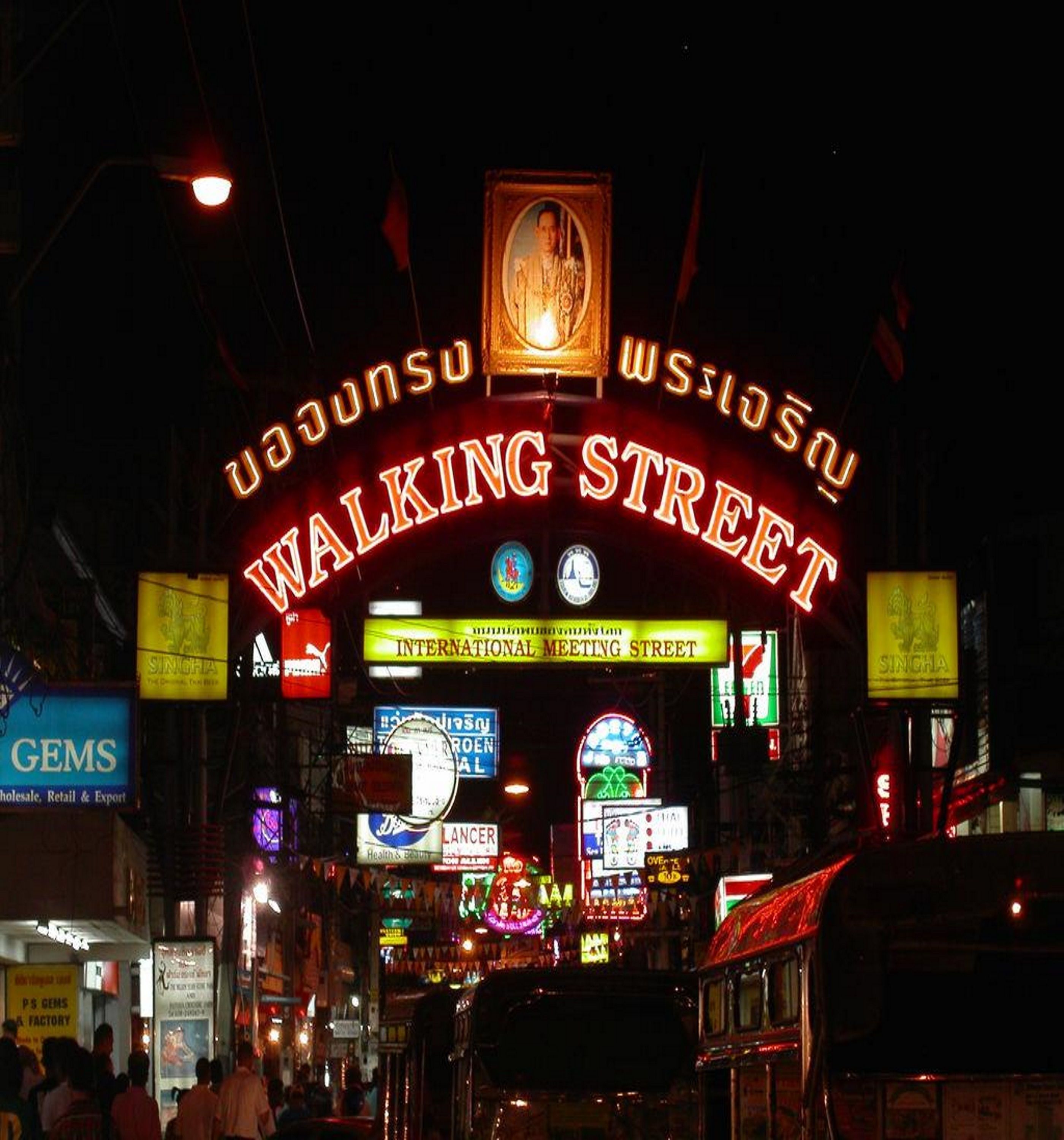 A brightly lit street with neon signs, including "Walking Street" and "International Meeting Street".