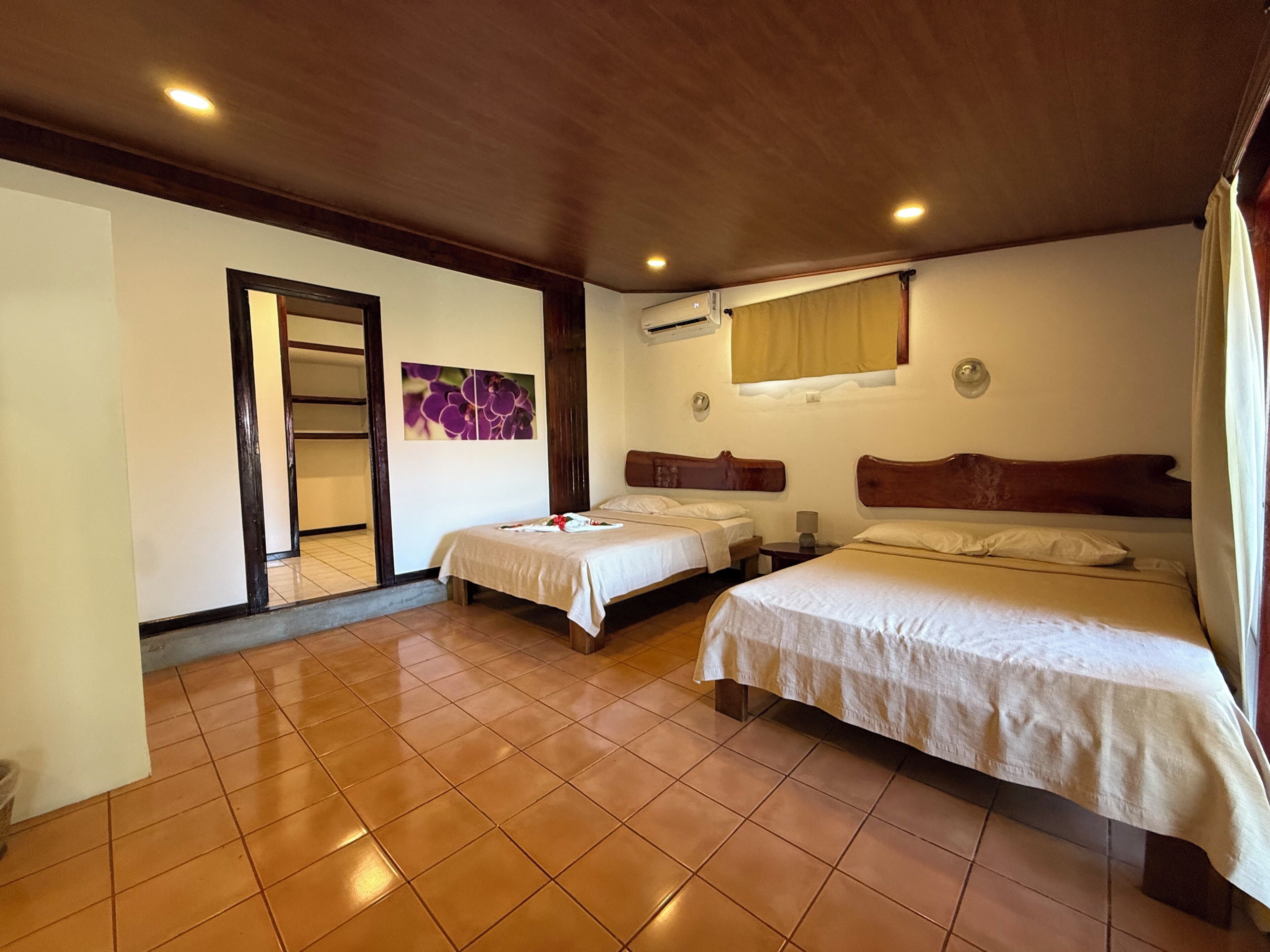 A hotel room with two beds, a bathroom with a shower, and a large mirror.