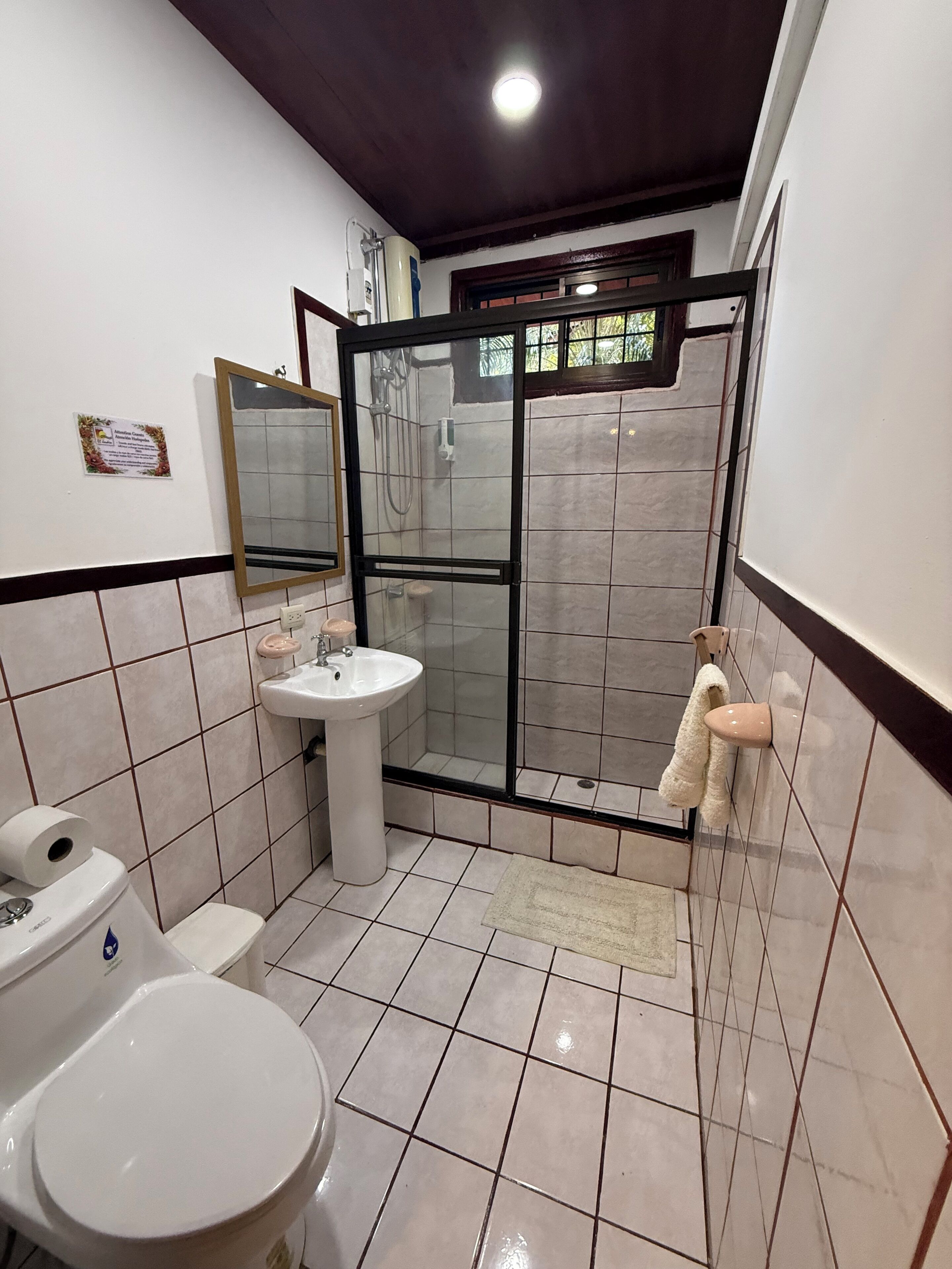A bathroom with a toilet, sink, and shower stall.