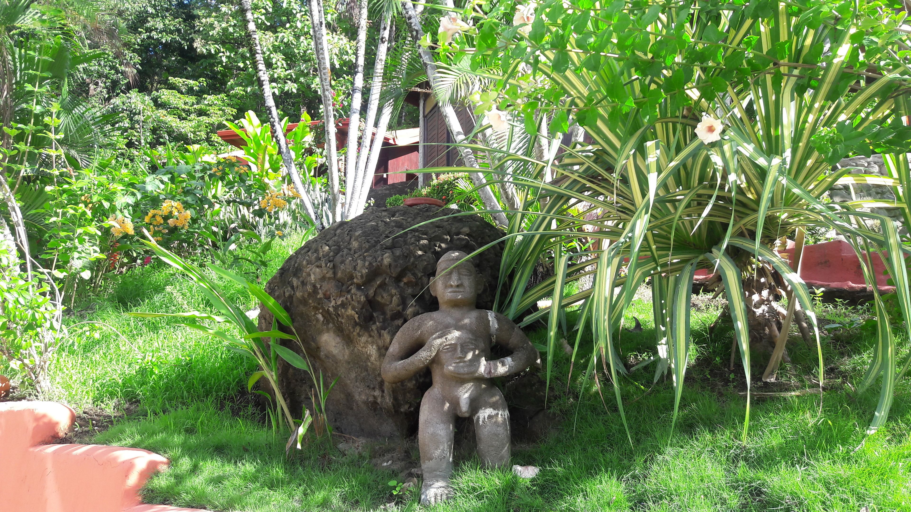 Un jardín con una estatua de un niño y una gran formación rocosa.