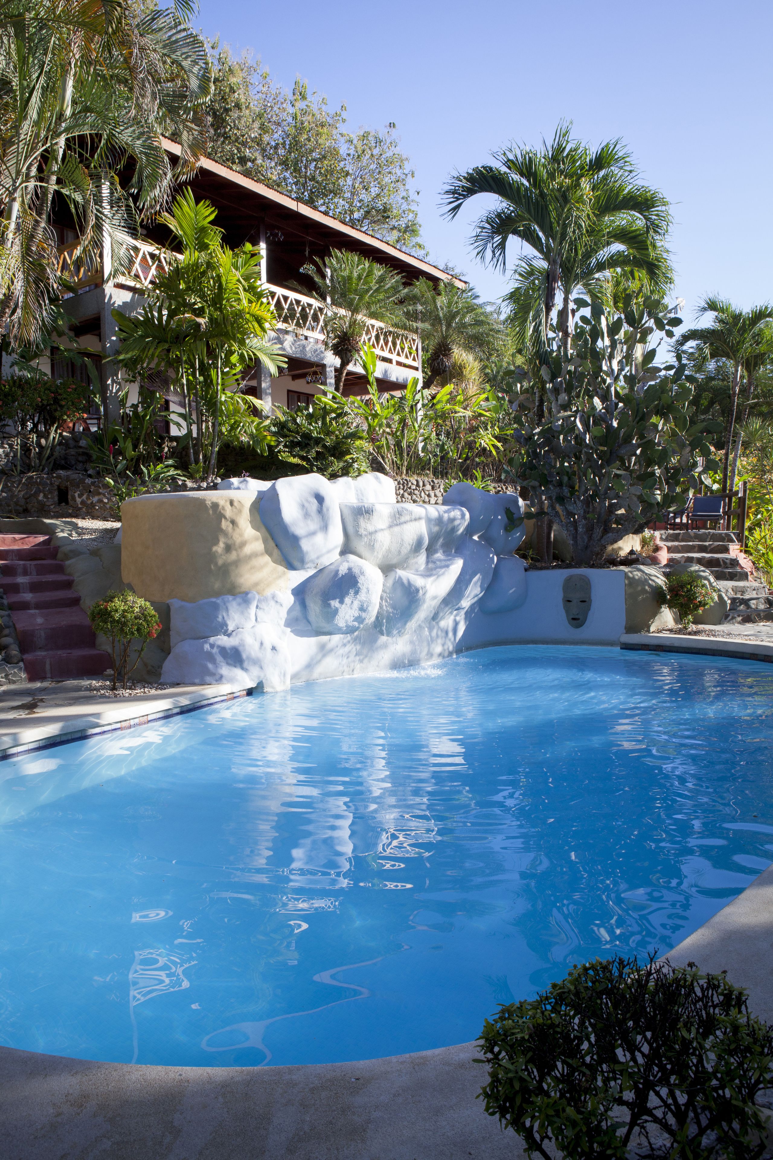 A pool with a rock formation and palm trees.