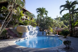 A pool surrounded by tropical plants and a waterfall feature. - Hotel El Jardín (Cóbano)