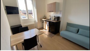 Een kleine keuken met een eettafel, stoelen, een ingebouwde oven en een raam.