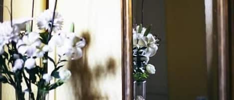 A window with a mirror reflecting a bouquet of white flowers.