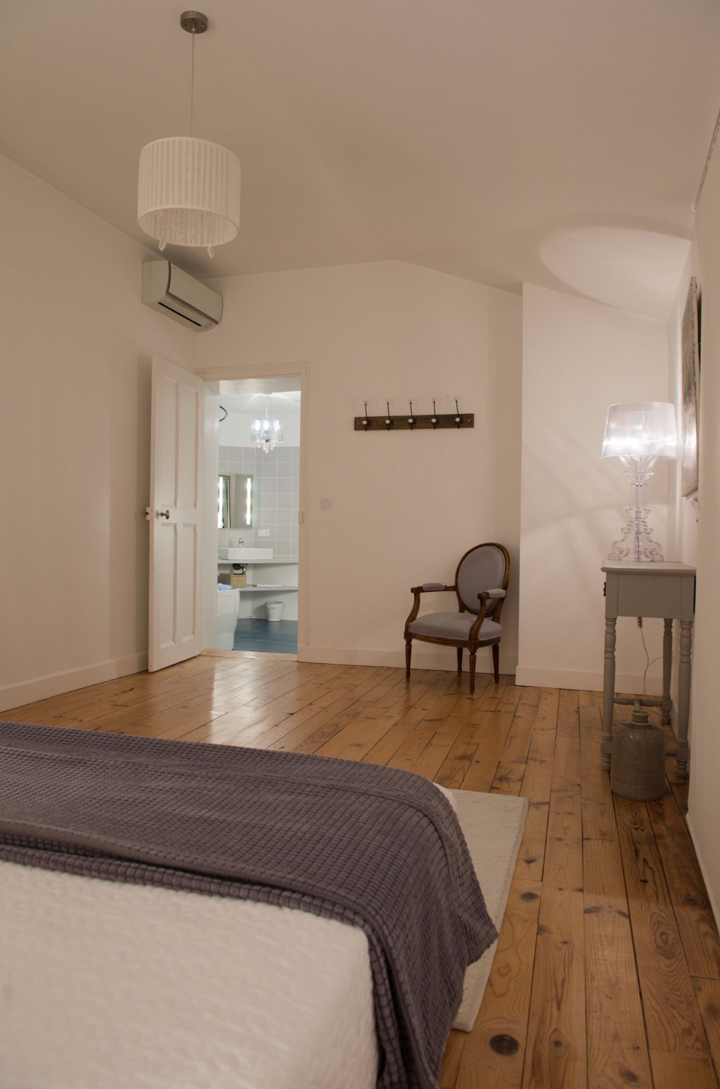 Un dormitorio con cama, una silla, una mesa y una araña.
