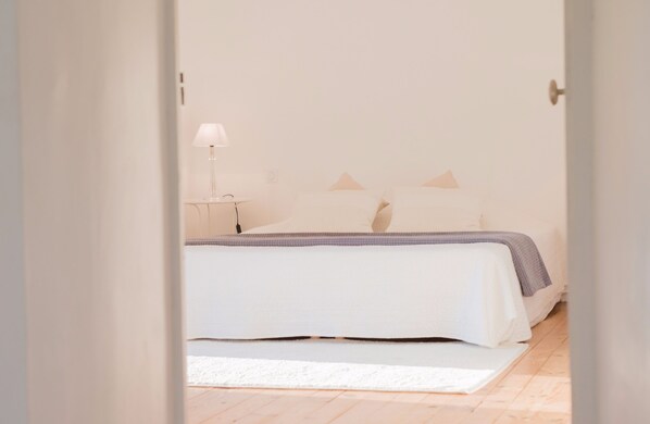 A bedroom with a bed, pillows, a bedside table, and a lamp.