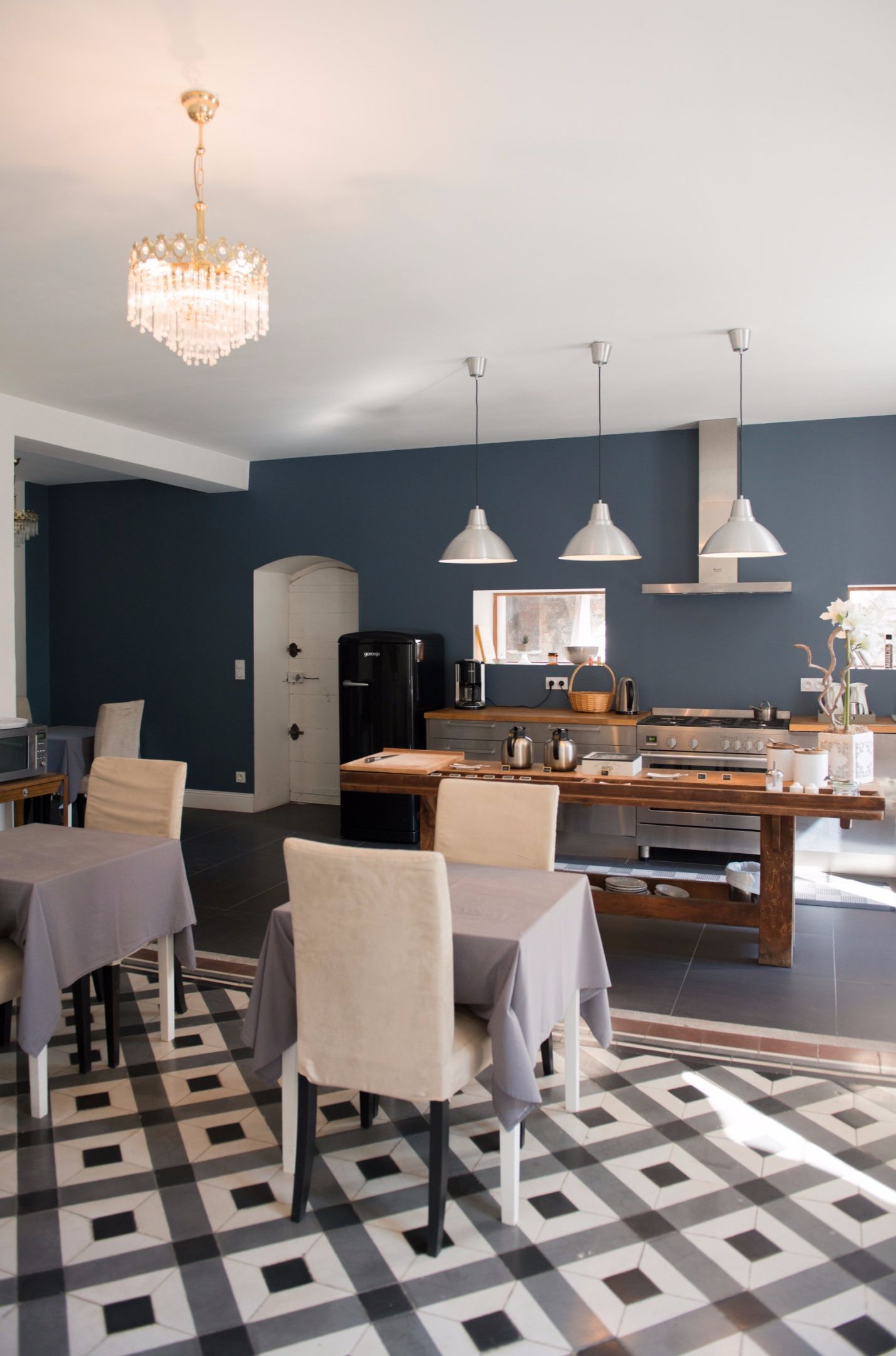 Een moderne keuken met een zwarte koelkast, een houten eettafel en hanglampen.