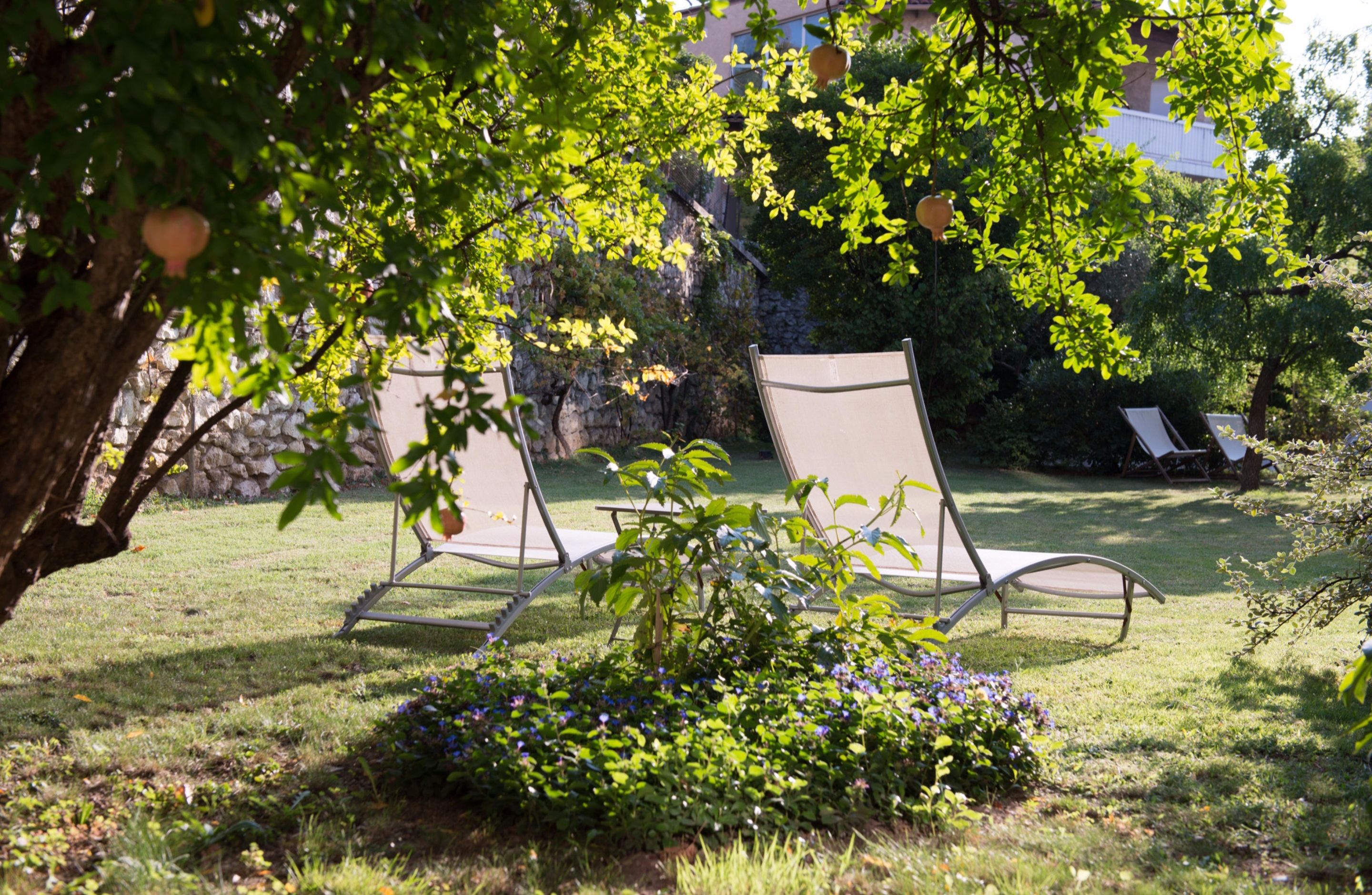 Un jardín con dos sillones de descanso y un pequeño macizo de flores.