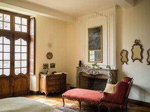 A room with a wooden door, a fireplace, a red upholstered chair, and a dresser with drawers.