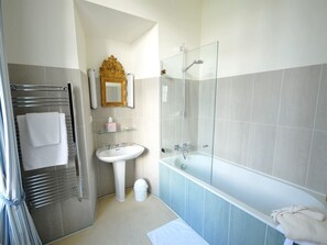 A modern bathroom with a glass-enclosed shower, a white sink, and a towel rack.
