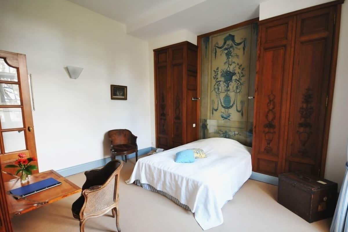 Ein Schlafzimmer mit einem Bett, einem Schreibtisch, einem Stuhl und einem Kleiderschrank.