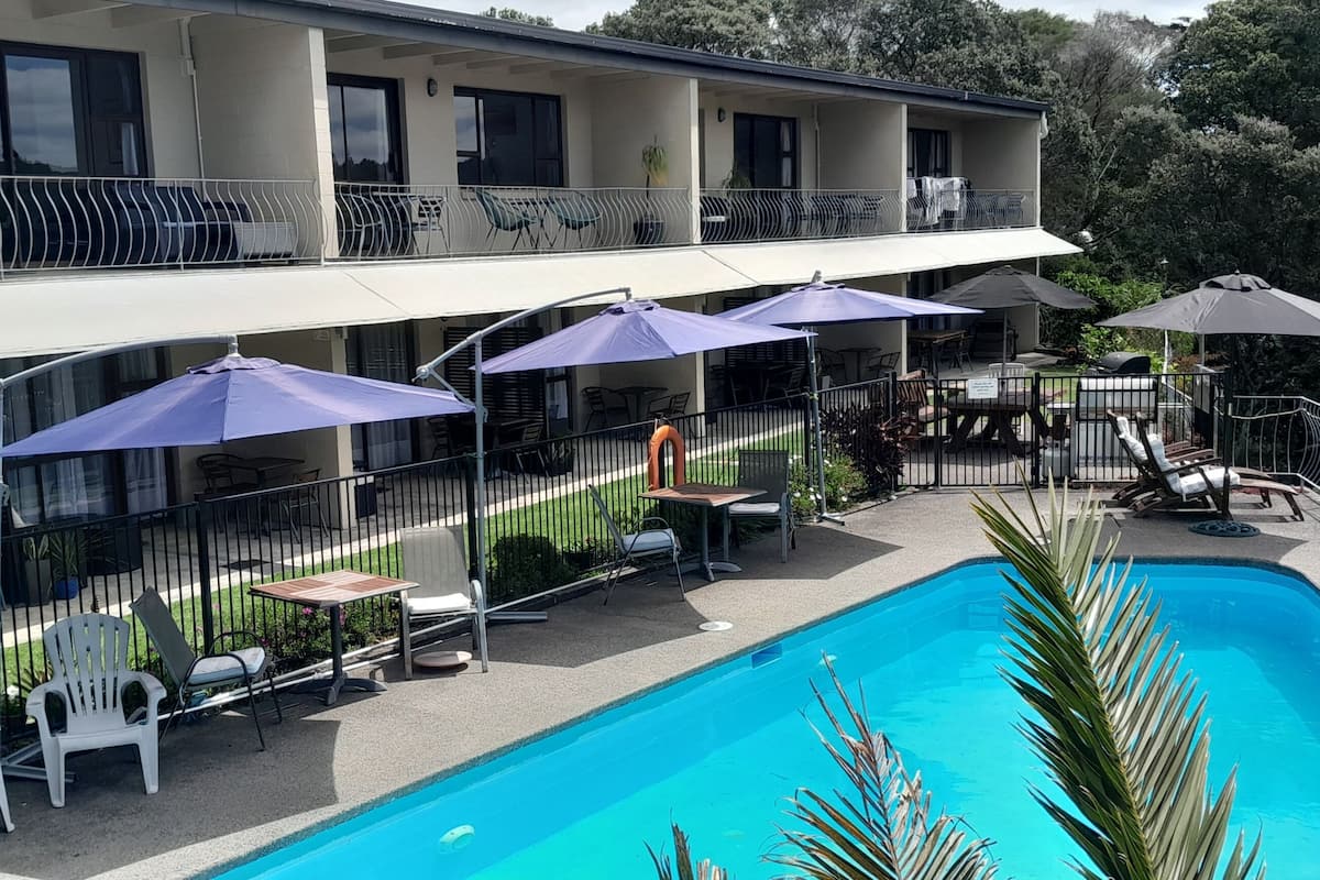 A hotel with a swimming pool, outdoor seating, and a covered patio area.