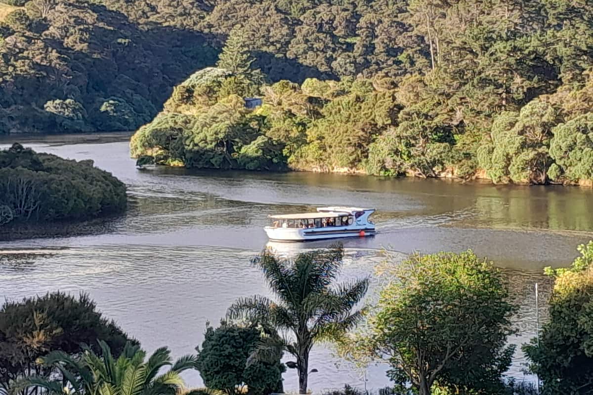 A river with a boat, surrounded by dense forest and hills.