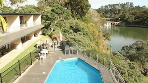 Un espace piscine avec des chaises longues et une vue sur un lac.