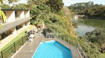 A pool area with lounge chairs and a view of a lake.