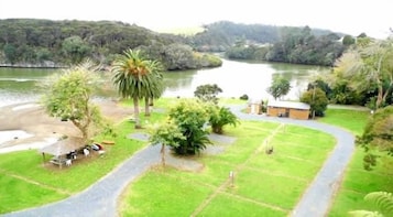 A riverside property with a paved path, a small building, and lush greenery.