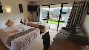 Une chambre d’hôtel avec deux lits, une télévision, un balcon avec vue et un coin salon.