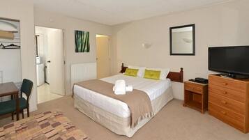 A hotel room with a bed, a television, a dresser, a desk, and a chair.