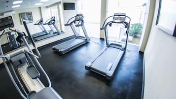 Een sportschool met loopbanden, elliptische trainers en een hometrainer.