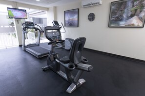 A gym with treadmills and an elliptical machine, a TV on the wall, and a clock. - Holiday Inn Express Guadalajara Aeropuerto by IHG (El Salto)