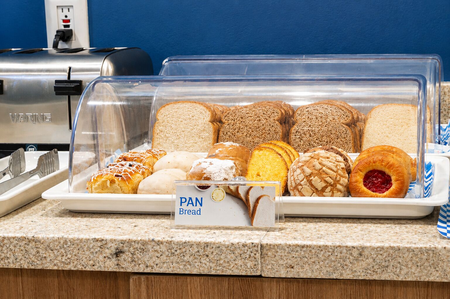 Mostrador de panadería con distintos tipos de pan y pasteles.
