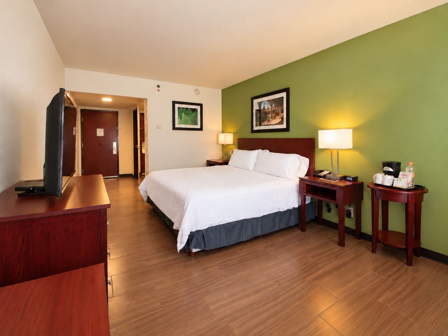 Une chambre d’hôtel comprenant un lit, des tables de chevet, une télévision et une porte donnant sur une autre pièce.