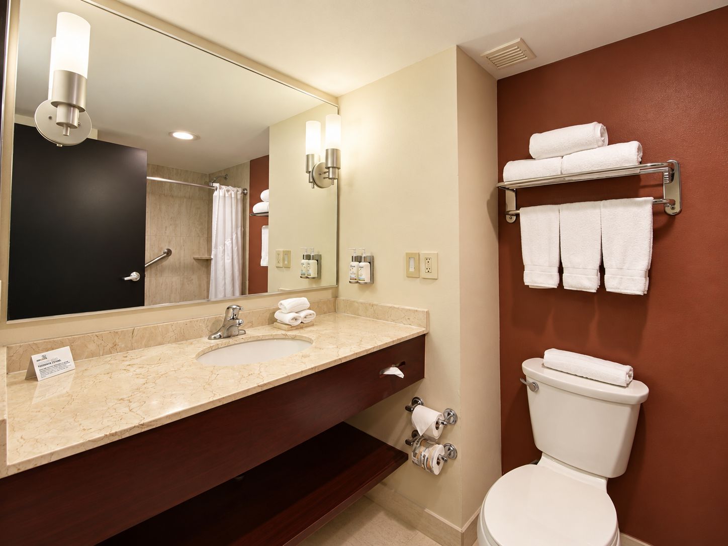 A bathroom with a sink, mirror, towel rack, and toilet.