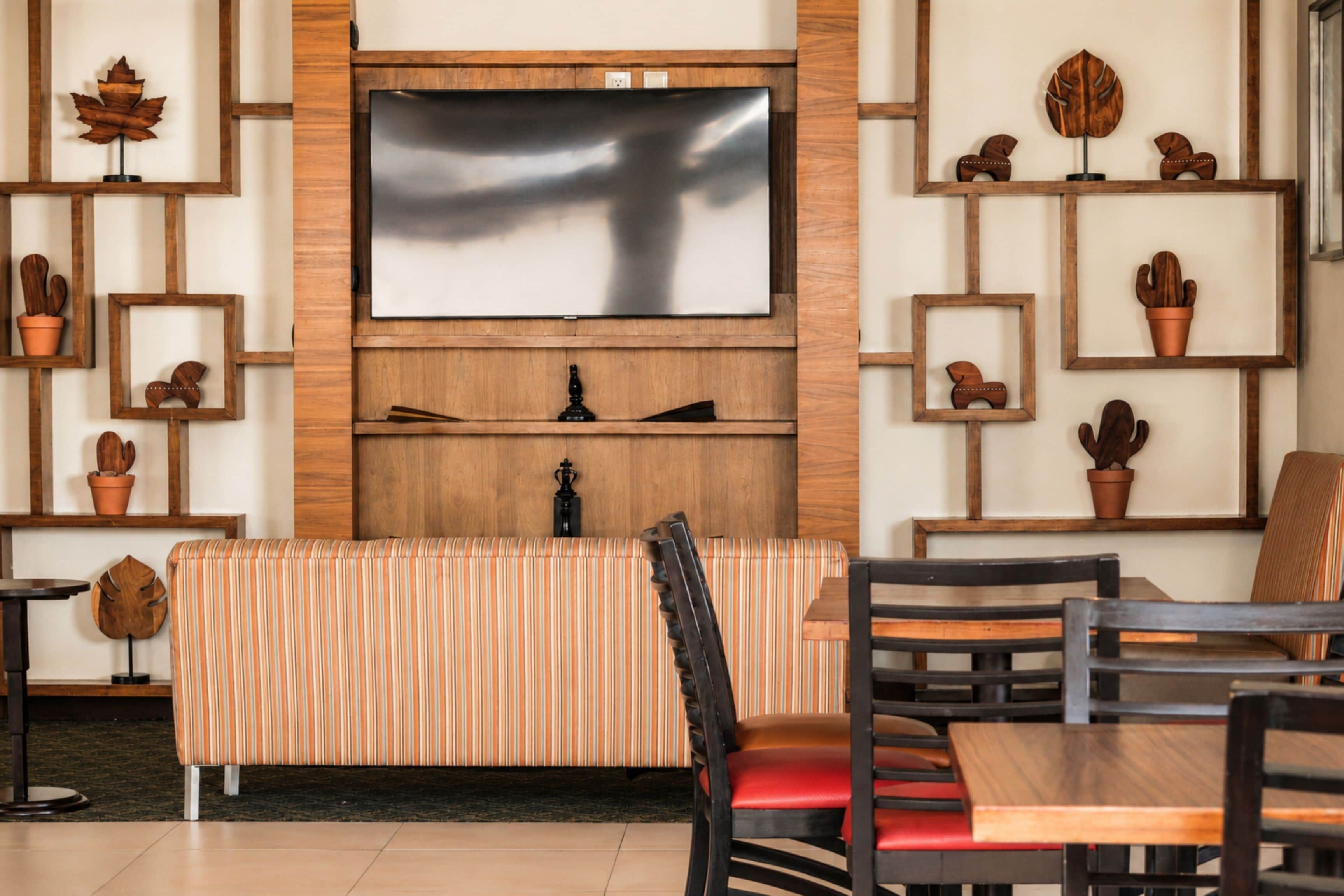 Un interior moderno con un panel de madera, un televisor de pantalla plana, un banco acolchado y un comedor con sillas y una mesa.