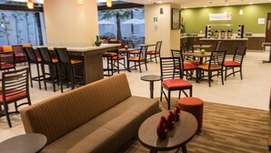 Un vestíbulo de hotel con una zona de estar, un bar y una recepción.