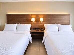 A hotel room with two beds, a wooden headboard, bedside lamps, a nightstand with a phone and remote control, and a clock. - Holiday Inn Express Guadalajara Aeropuerto by IHG (El Salto)