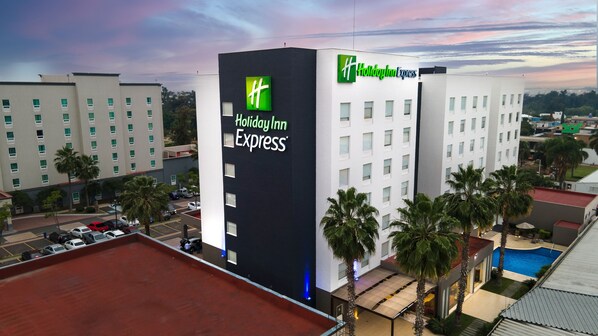Ein Holiday Inn Express Gebäude mit auffälliger Beschilderung, umgeben von Palmen und einem Parkplatz.