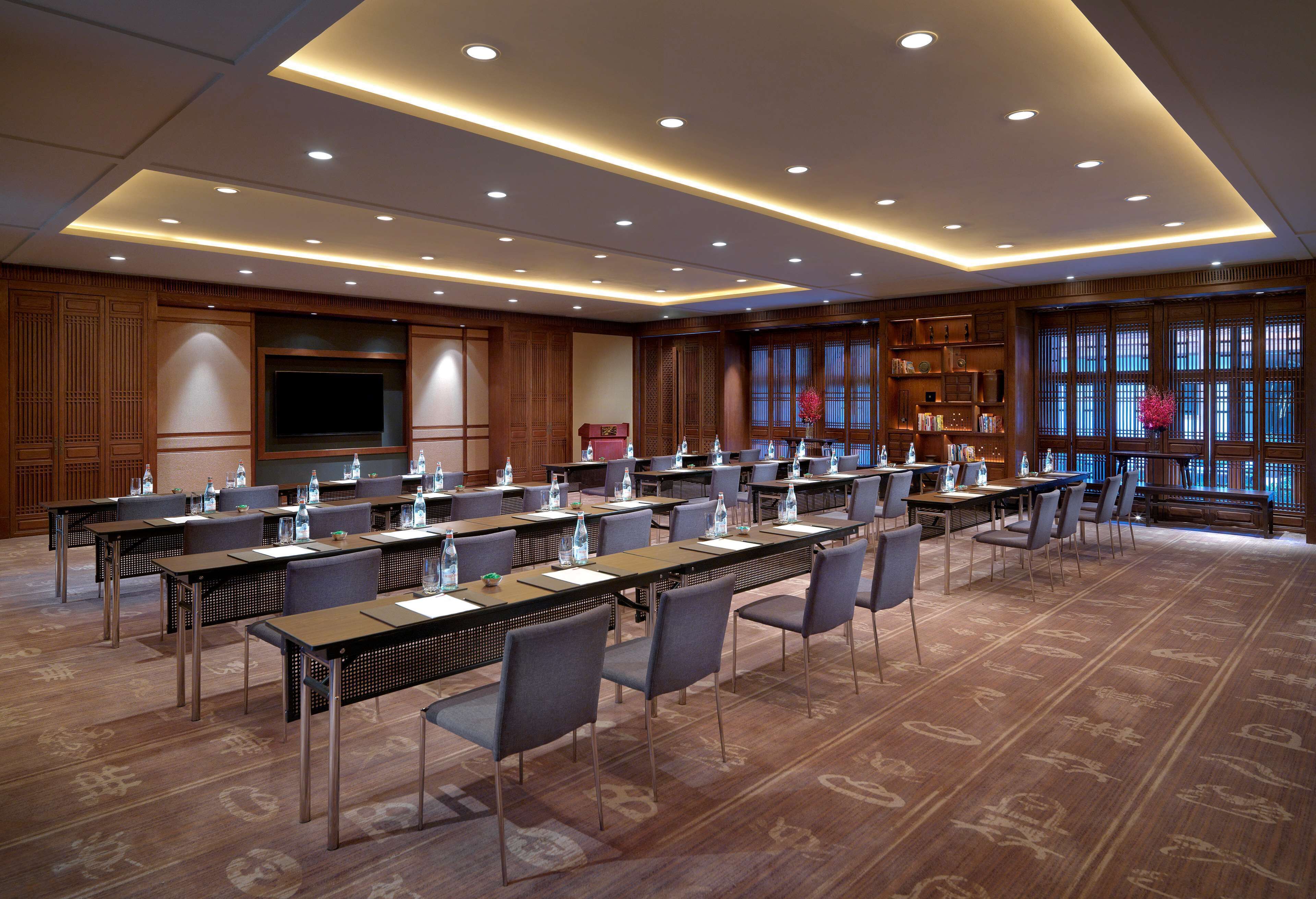 A conference room with multiple tables and chairs, equipped with water bottles and name cards.
