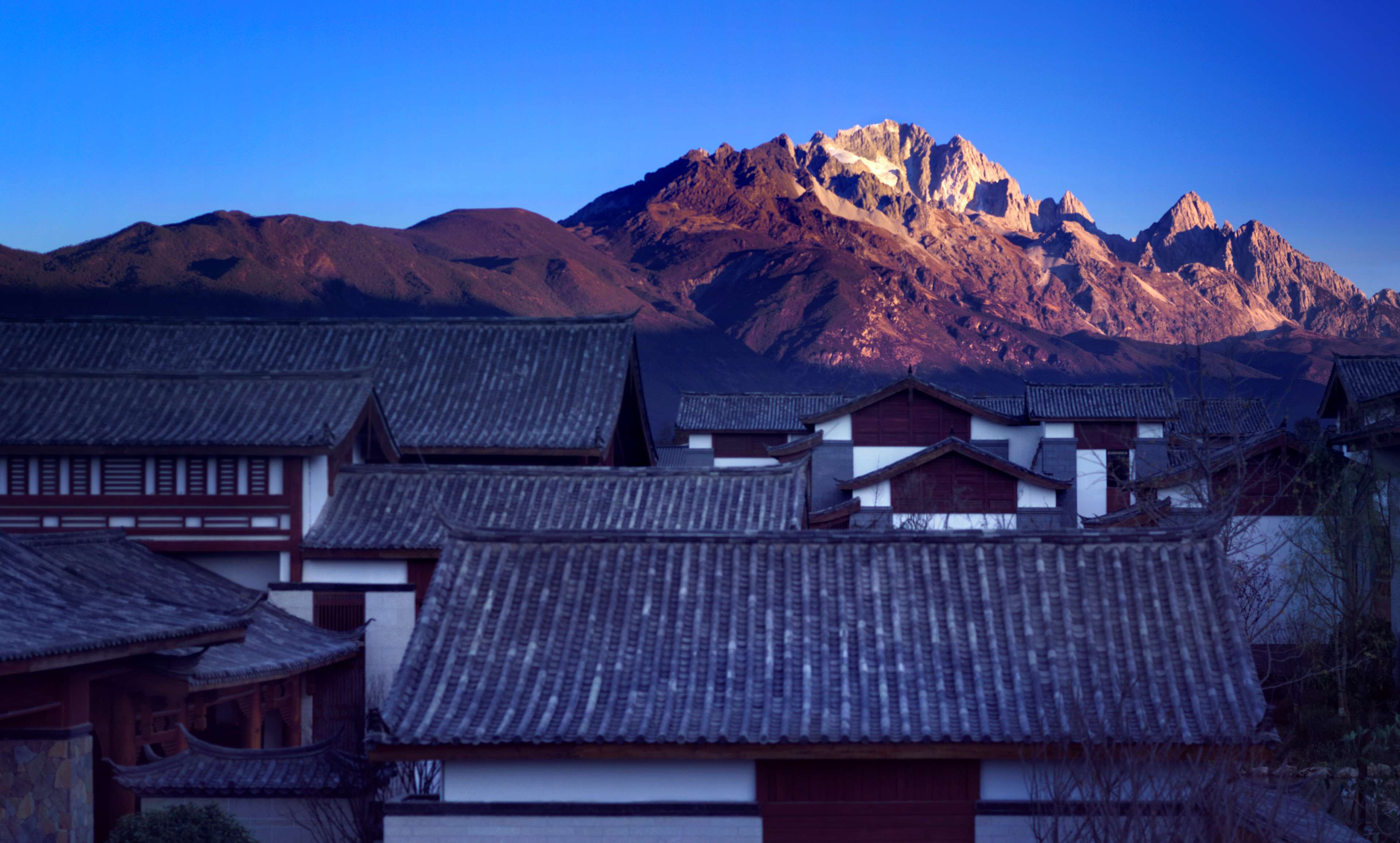 Traditional buildings with tiled roofs and a mountain range in the background.
