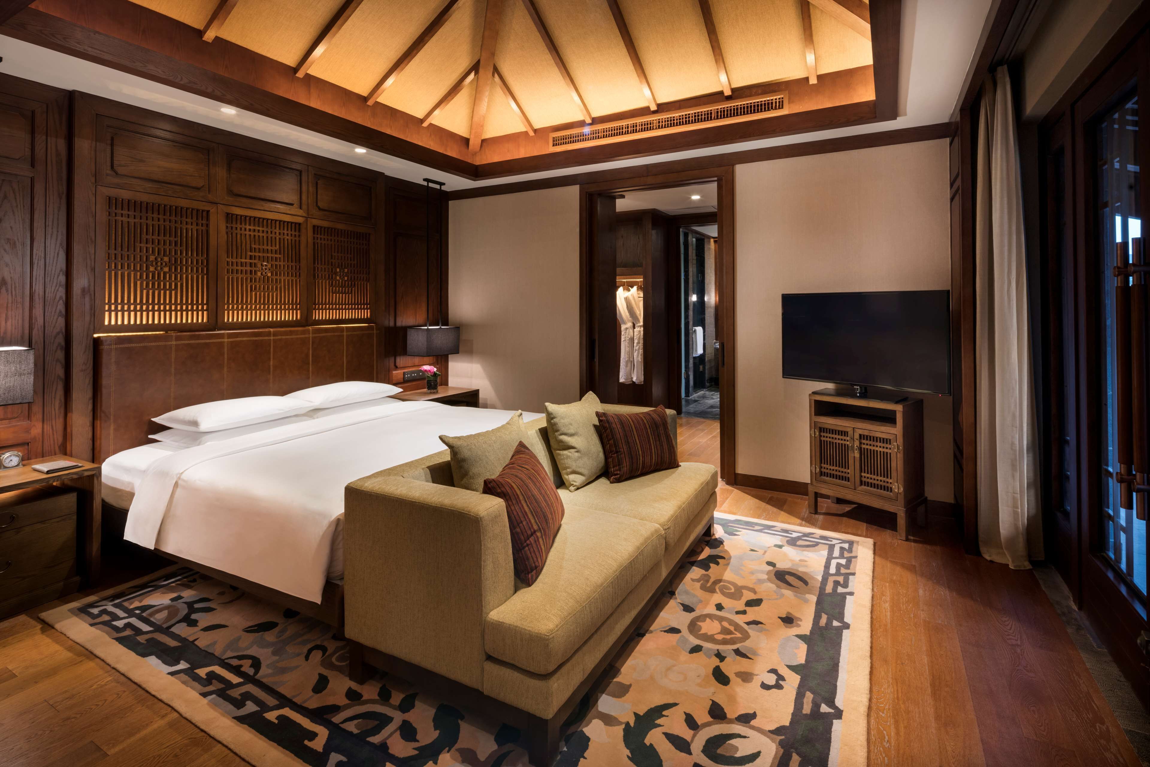 Een hotelkamer met een groot bed, een bank, een televisie en een kledingkast.
