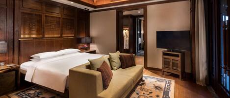 A hotel room with a large bed, a sofa, a TV, and a wardrobe.