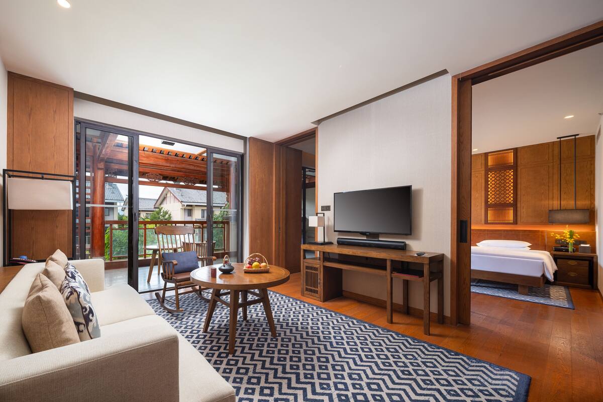 Ein modernes Hotelzimmer mit Sofa, Fernseher und einer Essecke mit Tisch und Stühlen.