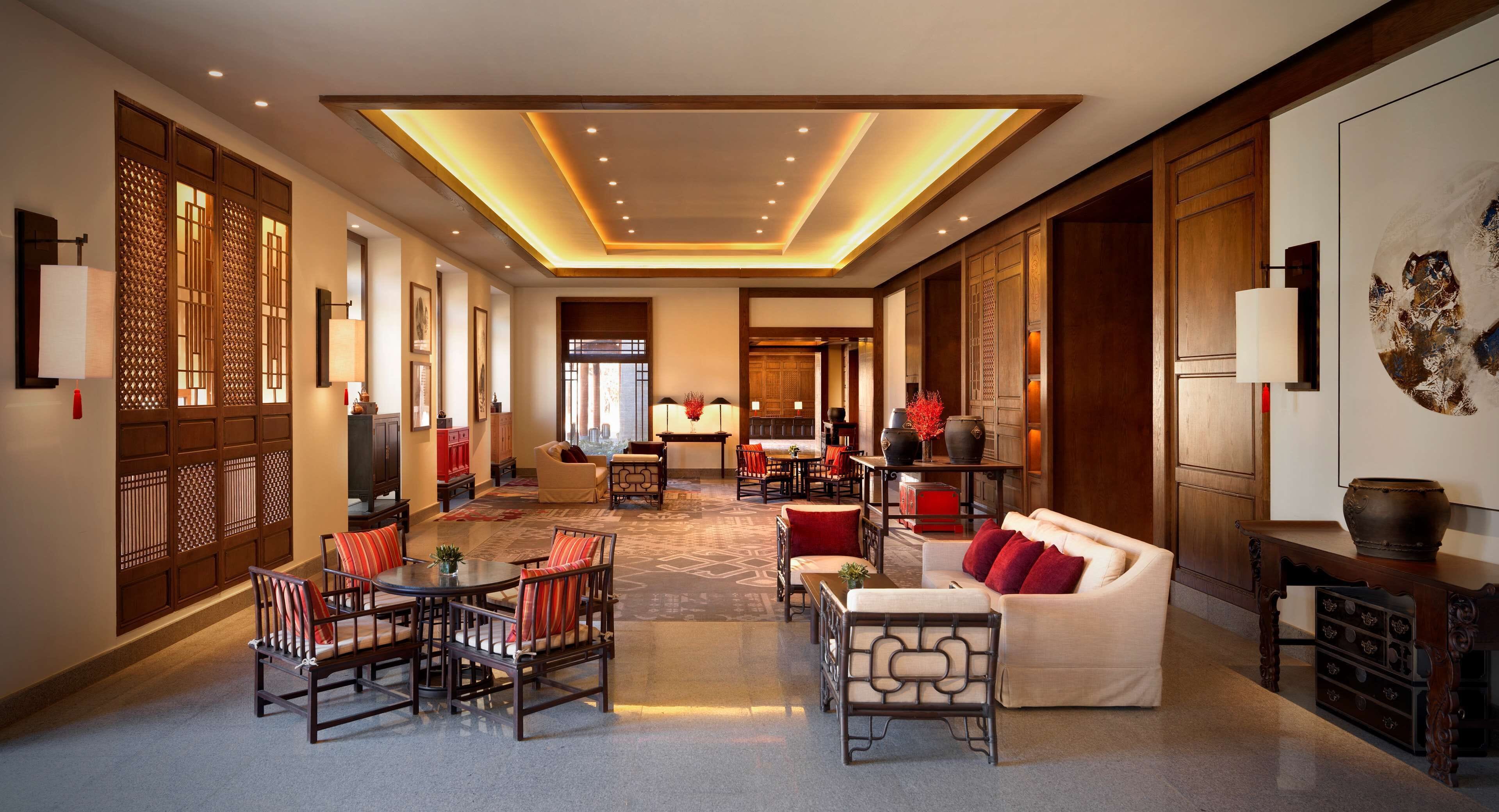A spacious hotel lobby with a central seating area, a reception desk, and traditional decor.