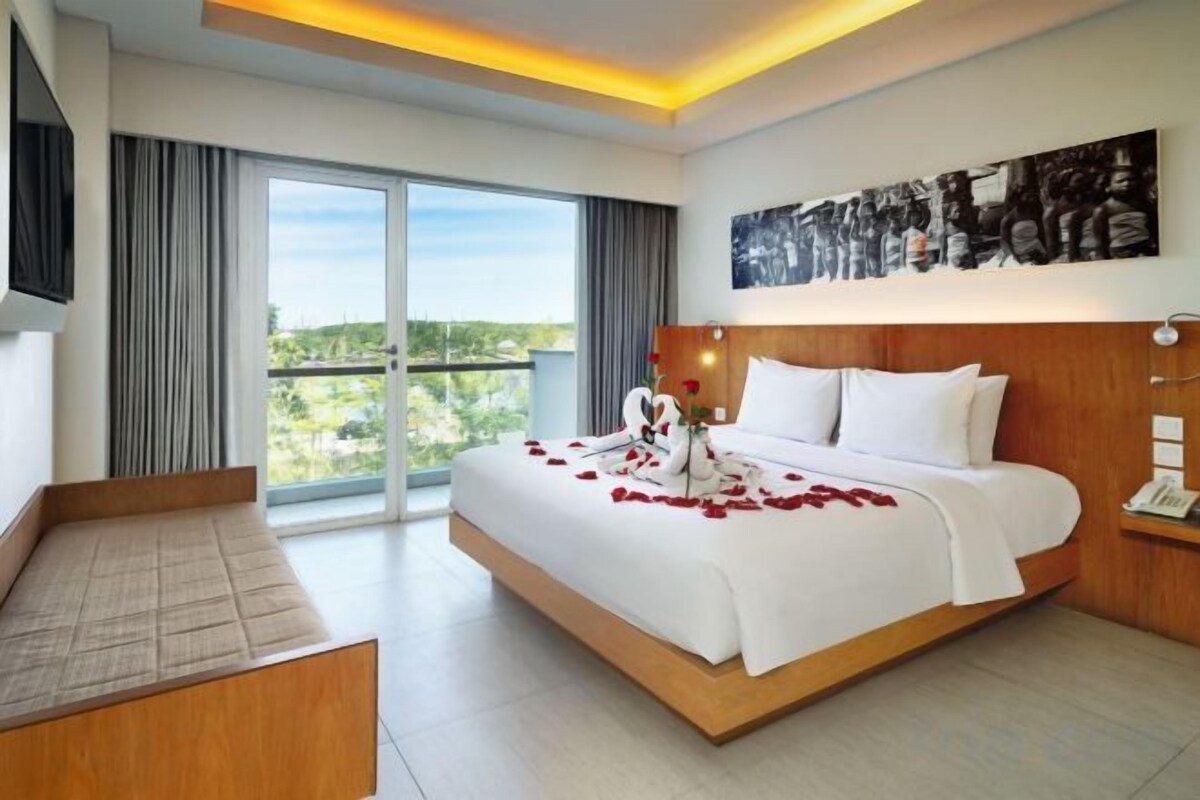 Quarto de hotel com uma cama grande, área de estar, televisão de tela plana e vista para o exterior.