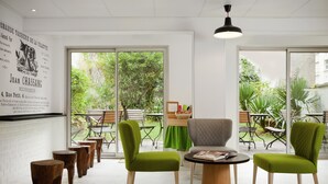 A modern interior with a green chair, a grey armchair, and a wooden table. - ibis Styles Paris Buttes Chaumont (Paris)