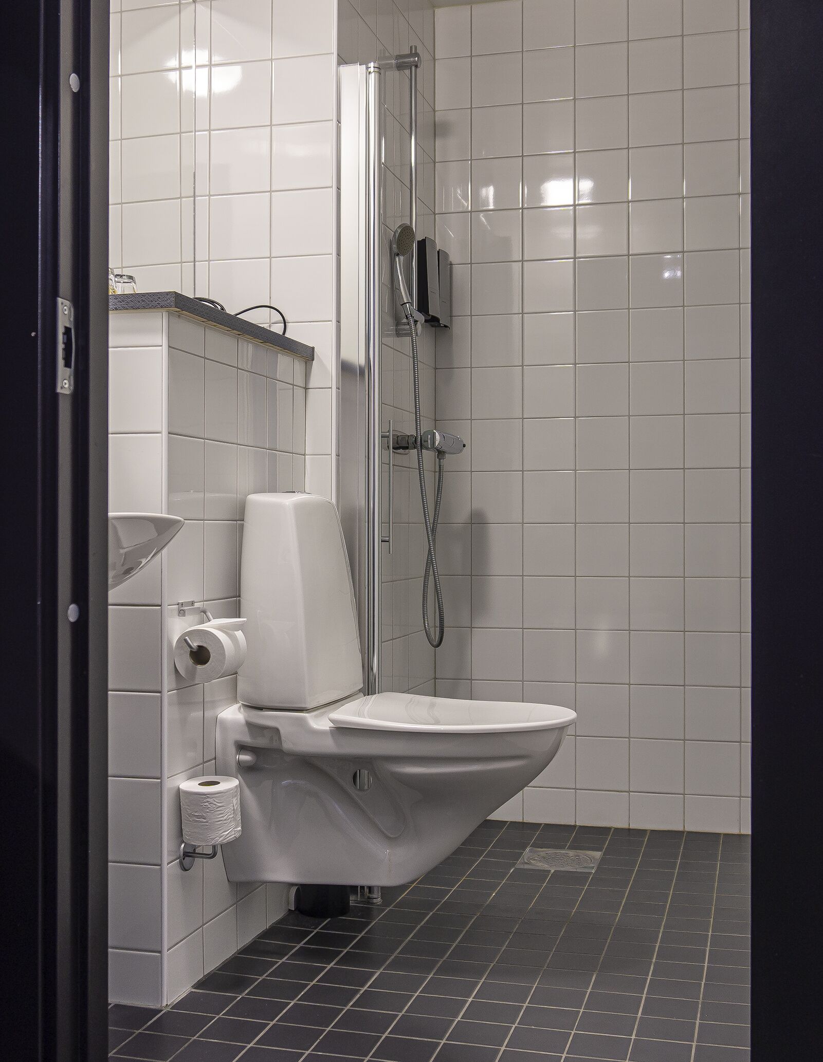 A modern bathroom with a white toilet, a shower area, and a tiled floor.