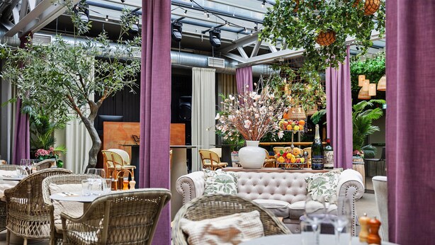 An outdoor seating area with wicker furniture, a tufted sofa, and a variety of plants and flowers. - Best Western Hotel Norrkoping City (Norrköping)