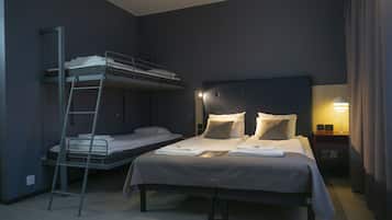 Ein Hotelzimmer mit Etagenbett, einem Einzelbett, einem Nachttisch mit Lampe und einem an der Wand montierten Fernseher.