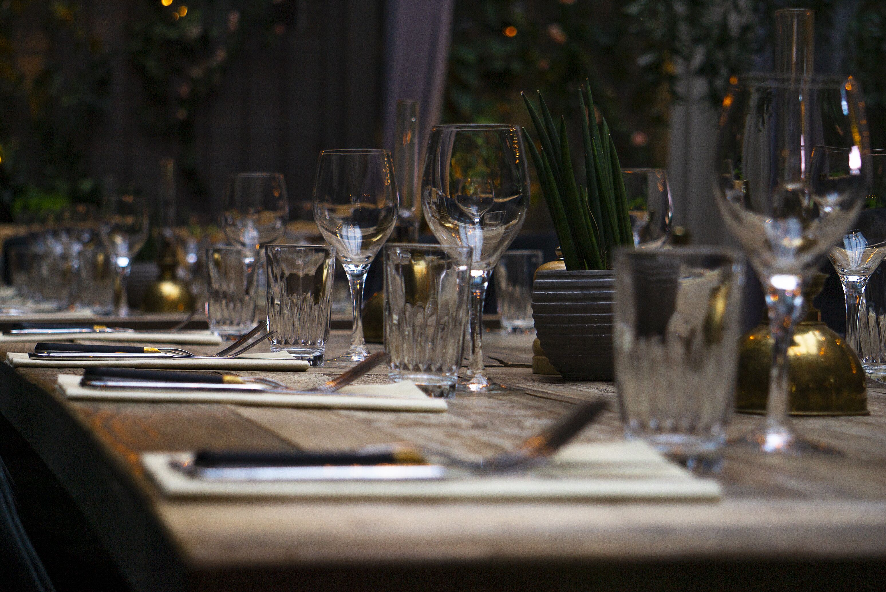 A dining table set with multiple wine glasses, cutlery, and napkins.