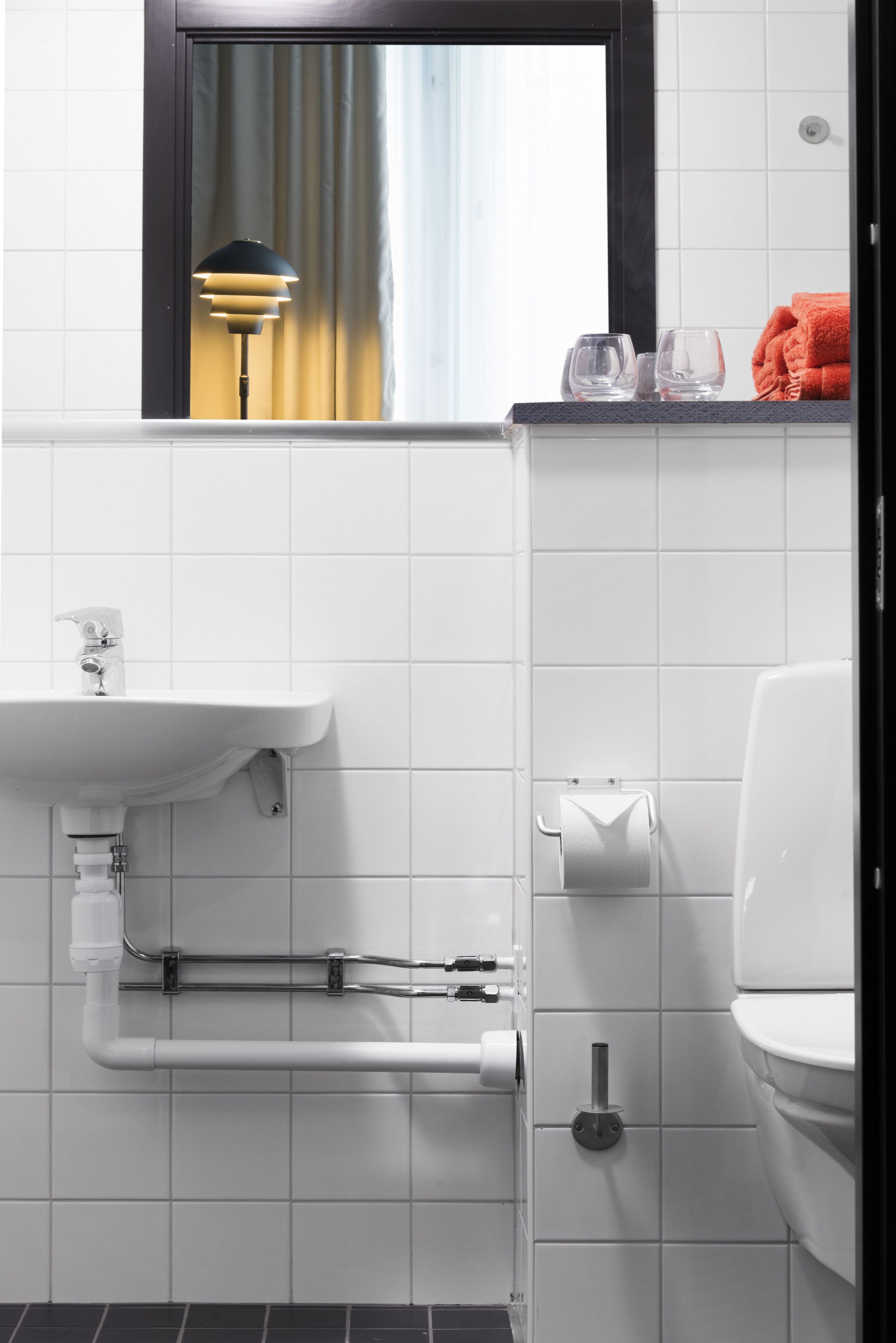 Un baño moderno con un lavabo blanco, inodoro y una ventana con vista a una cortina.