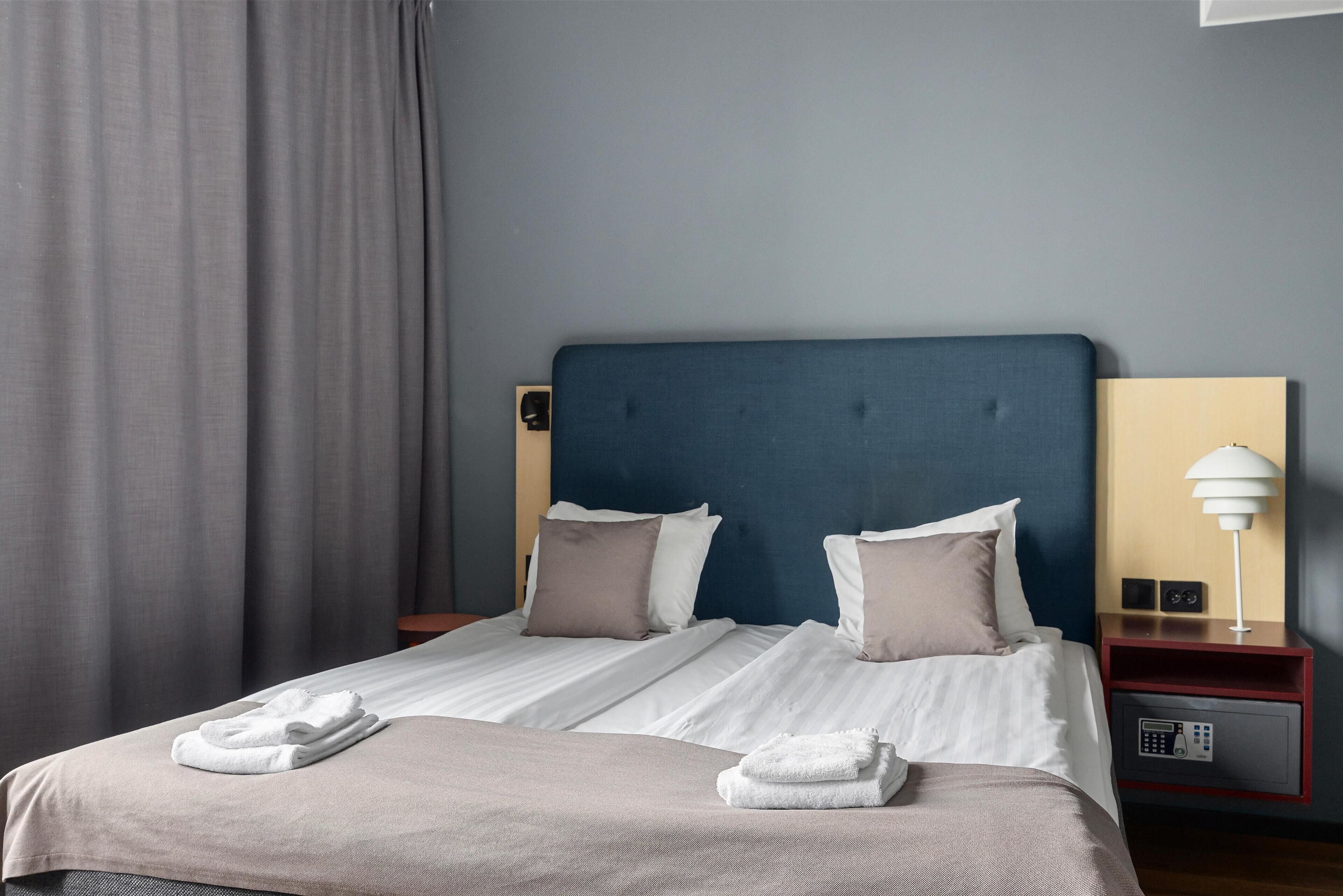 Una cama bien hecha con sábanas blancas, dos almohadas y una toalla doblada sobre la cama.