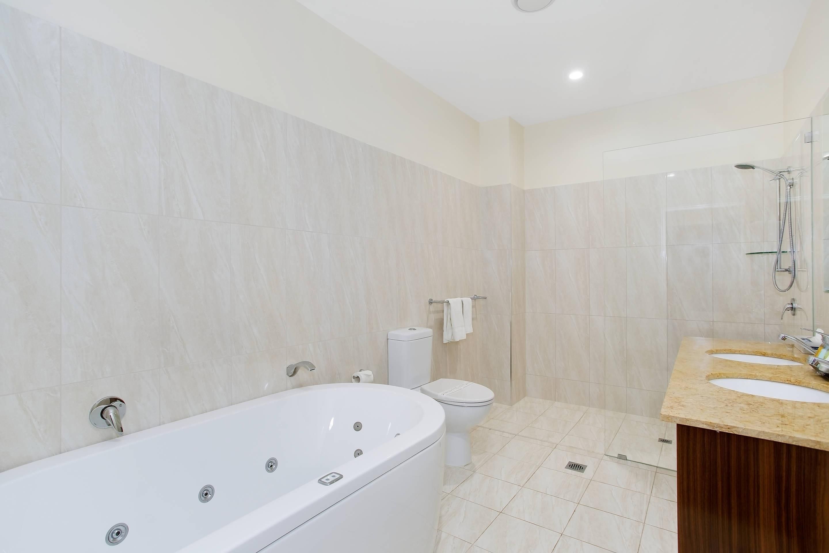 Un baño moderno con una bañera independiente, un inodoro y un lavamanos doble.