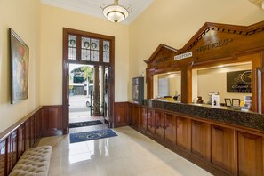 A reception area with a wooden reception desk, a bench, and a door leading outside. - Quality Hotel Regent Rockhampton (Rockhampton)
