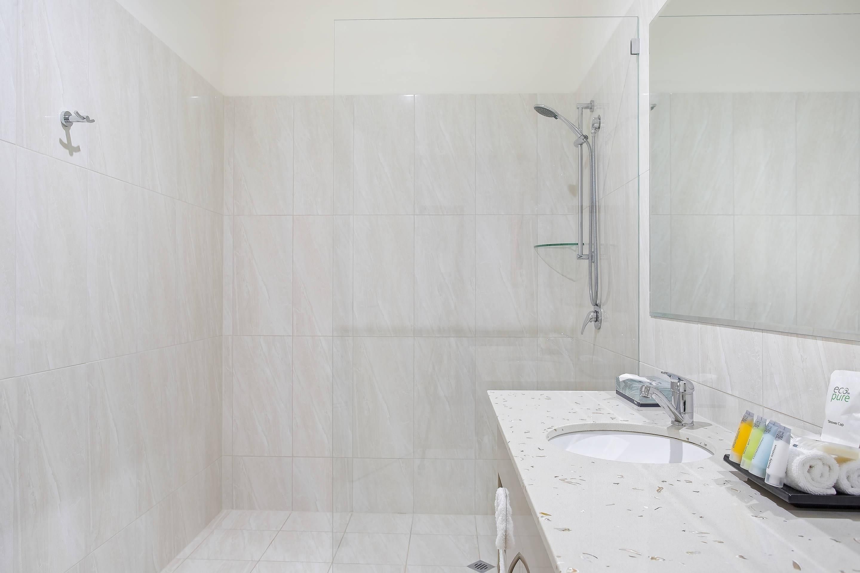 Un baño moderno con ducha, lavamanos y espejo.